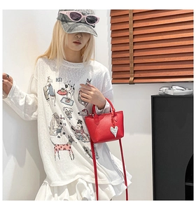 Détail du mini sac seau en cuir rouge avec pendentif cœur et texture lychee