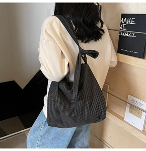 Detail of checkered canvas tote bag with decorative knot wide shoulder strap on model