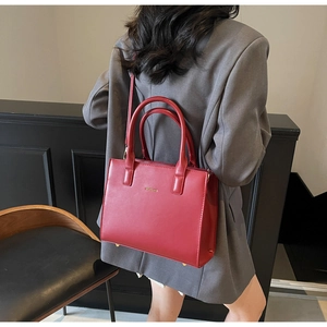 Detailed back view of a red leather tote bag with a fine matte texture and golden hardware