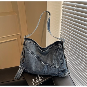 Detail of vintage blue denim tote with pockets, metal rivets and Y2K aesthetic