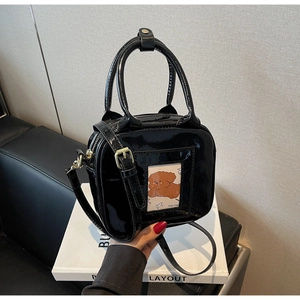 Close-up of black patent leather square bag with puppy card slot and thin shoulder strap