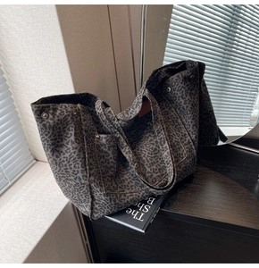 Close-up of leopard print canvas tote bag featuring contrast stitching and metal rivets