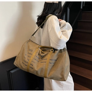 Detail of khaki canvas travel tote with reinforced handles and adjustable shoulder strap