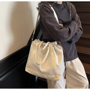Detail van gebroken witte tote bag met verstelbare schouderriem en trekkoordsluiting