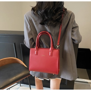 Model wearing a red matte leather crossbody tote bag with gold logo and dual handles