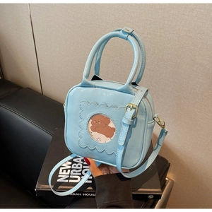 Macro shot of light blue crossbody bag featuring a cute cartoon dog window and gold hardware