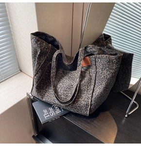 Close-up of leopard print canvas tote bag with brown straps and functional front pocket