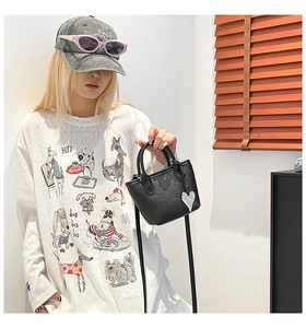 Détail d'un mini sac seau noir en cuir grainé avec pendentif en forme de cœur argenté