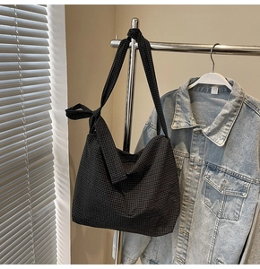 Detail of black plaid canvas tote bag with a decorative bow knot on the wide shoulder strap