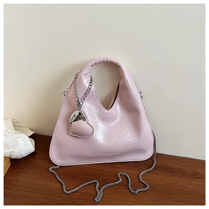 Detail of light pink patent leather handbag with glossy wrinkles and heart pendant