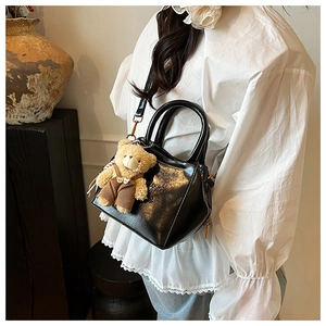 Polished black PU leather crossbody bag with cute plush bear charm detail on model