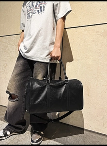 Detailed macro view of black faux leather gym bag with crocodile texture and strap