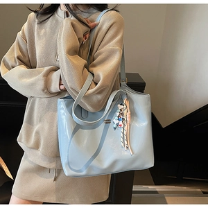 Close-up of light blue patent leather tote bag with stylish tassel and bead charms