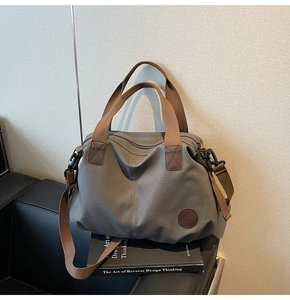 Detail view of water-resistant gym bag with durable webbing handles and leather brand logo