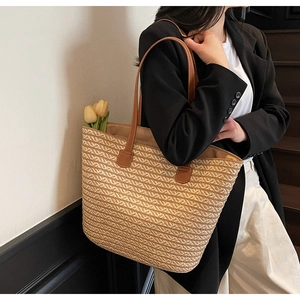 Detailed close-up of woven tote bag showing striped straw texture and brown leather straps