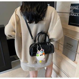 Detail of black glossy cylindrical bowling bag with a cute plush monster pendant charm