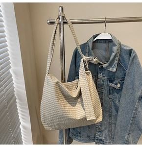 Detail of hobo bag showing checkered beige fabric and side ribbon knot strap