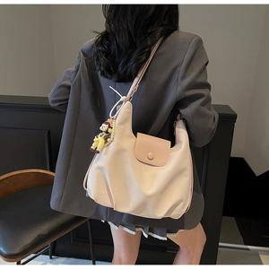 Detail of pink canvas hobo tote bag featuring cartoon girl charm and pearl strap accessory