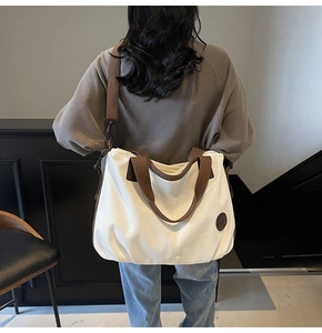 Detailed back view of a large cream canvas tote bag with brown straps on a model