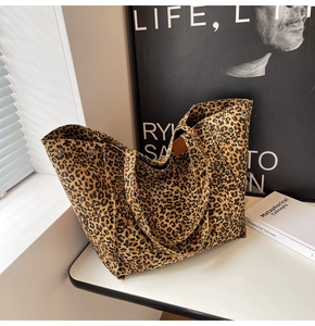 Detail of leopard print canvas tote bag featuring side metal snap button and leather handles