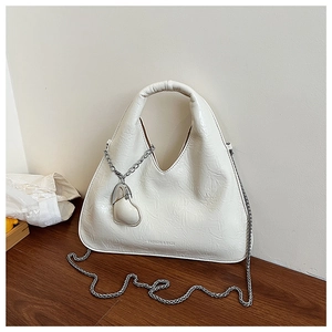 Close-up of the pleated faux leather texture and silver chain strap on a cream dumpling bag