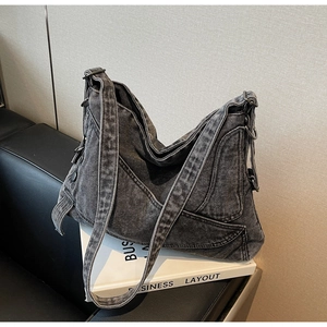 Detail of dark gray washed denim hobo bag with wide shoulder strap and metal ring