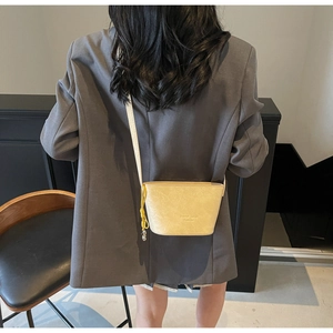 Détail du mini sac seau beige en similicuir avec breloque nœud jaune et bordure dentelle