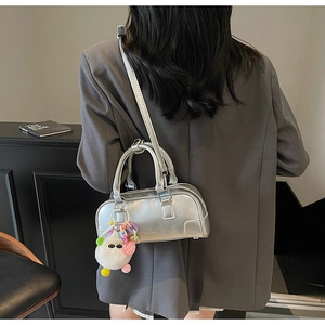 Detail of silver metallic Boston bag with furry charm on grey blazer outfit