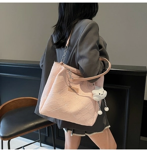 Detail of pink floral tote bag with leather strap and plush cloud charm on a model