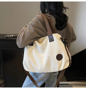 Detail of the high-capacity cream canvas tote bag with brown leather accents and straps
