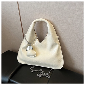 Close-up of pleated cream-white crossbody bag with silver chain and heart-shaped charm