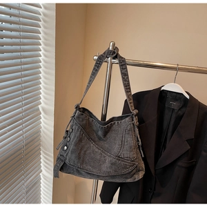 Detail of vintage grey denim hobo bag featuring silver rivets and wide strap design