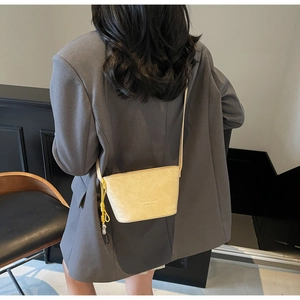 Détail de dos d'un mini sac seau beige avec texture gaufrée et pompon jaune vif
