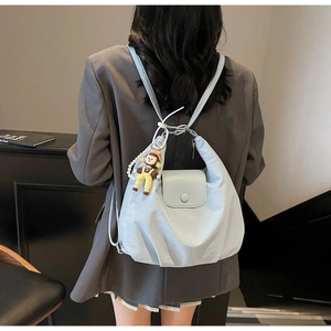 Detail showing light blue nylon shoulder bag with a cute cartoon girl doll charm