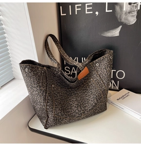 Close-up of leopard print canvas tote bag with metal rivet details and leather trim