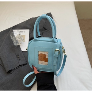 Detail view of light blue crossbody bag with gold hardware and stylish mini dog card slot