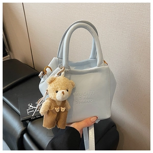 Detailed close-up of light blue PU leather handbag with decorative plush bear charm
