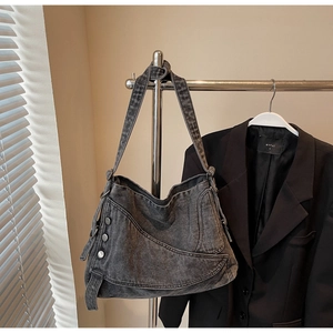 Detailed view of dark grey washed denim tote bag featuring metal studs and knotted strap