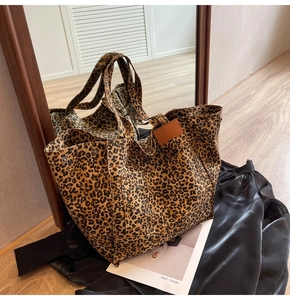 Macro detail of leopard print canvas tote bag with side leather tag and metal rivets