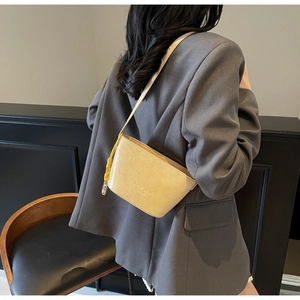 Détail du sac seau en cuir jaune clair avec surface texturée et gland jaune vif