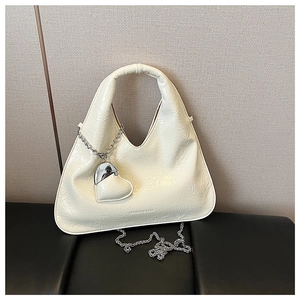 Detail of cream crossbody bag with crinkled patent leather and silver heart charm