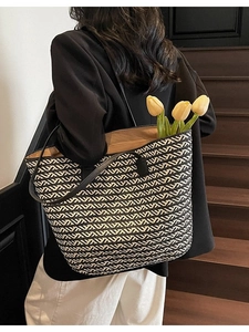 Chic black and white woven tote bag with leather straps on a model's shoulder