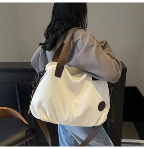 Detail of white canvas tote bag with brown straps shown on person for size and scale