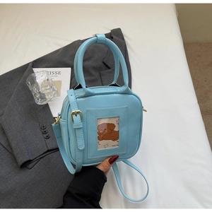 Detail of light blue glossy handbag with mini teddy bear card slot and gold zipper