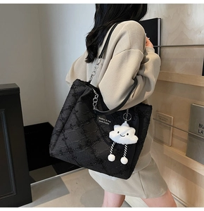 Detail of a large black quilted tote bag with sequins and a cute cloud charm