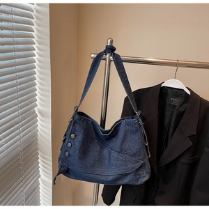 Detail of vintage denim crossbody hobo bag featuring silver metal button accents