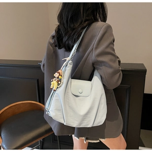 Detail view of a light blue large capacity tote bag with a cartoon doll charm and pearls
