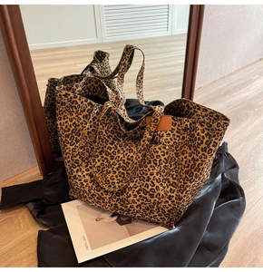 Detailed close-up of large canvas tote bag featuring classic leopard print and metal rivets