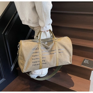 Close-up of olive green canvas travel duffle bag with leather handles and bold text prints