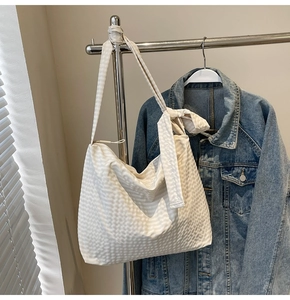 Macro detail of beige checkered tote bag featuring knotted shoulder strap and textured fabric